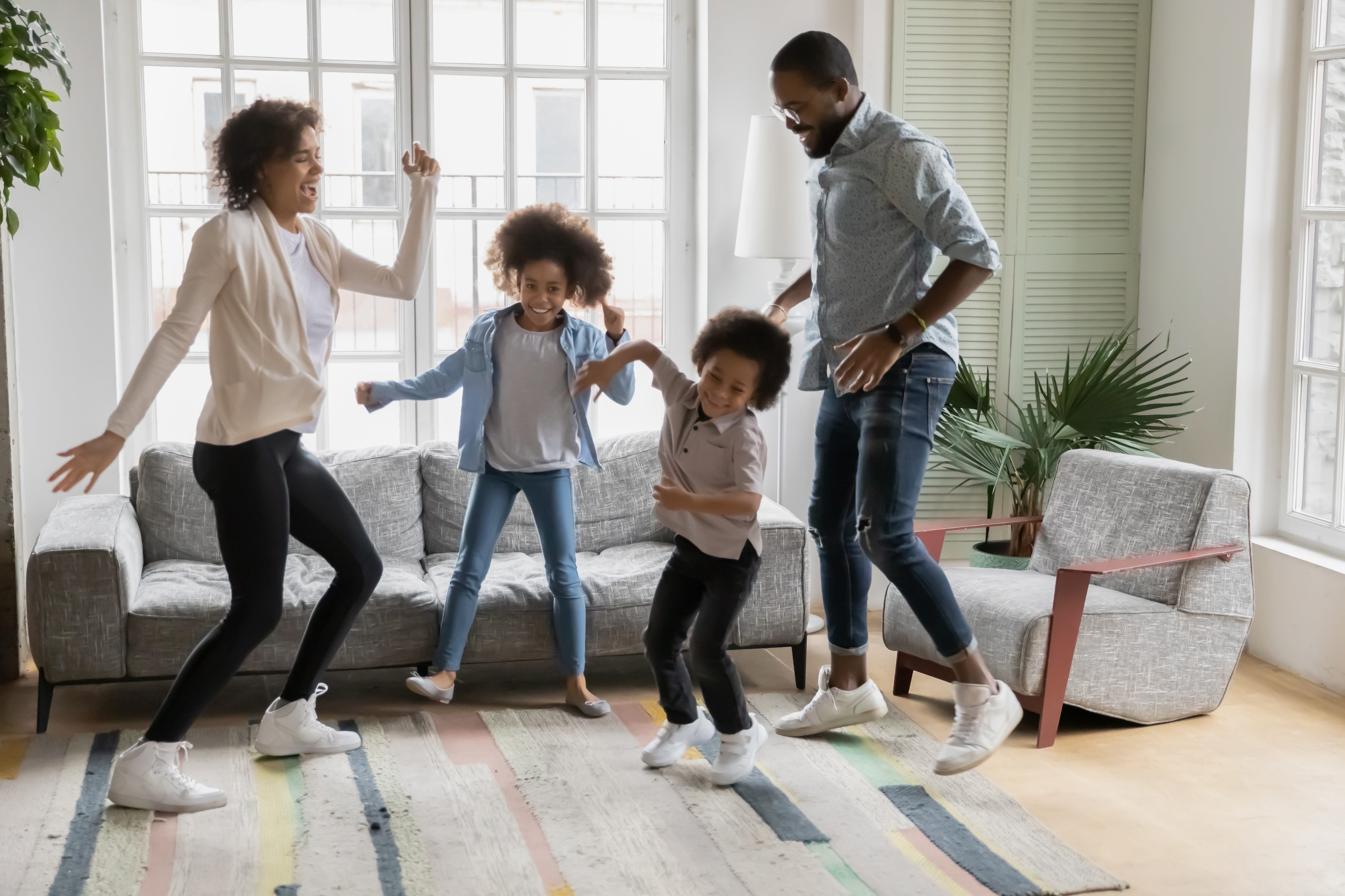 Full length view African ethnicity family dancing together in living room at new first home, young couple and little kids having fun listening music enjoy life cool weekends free time activity concept